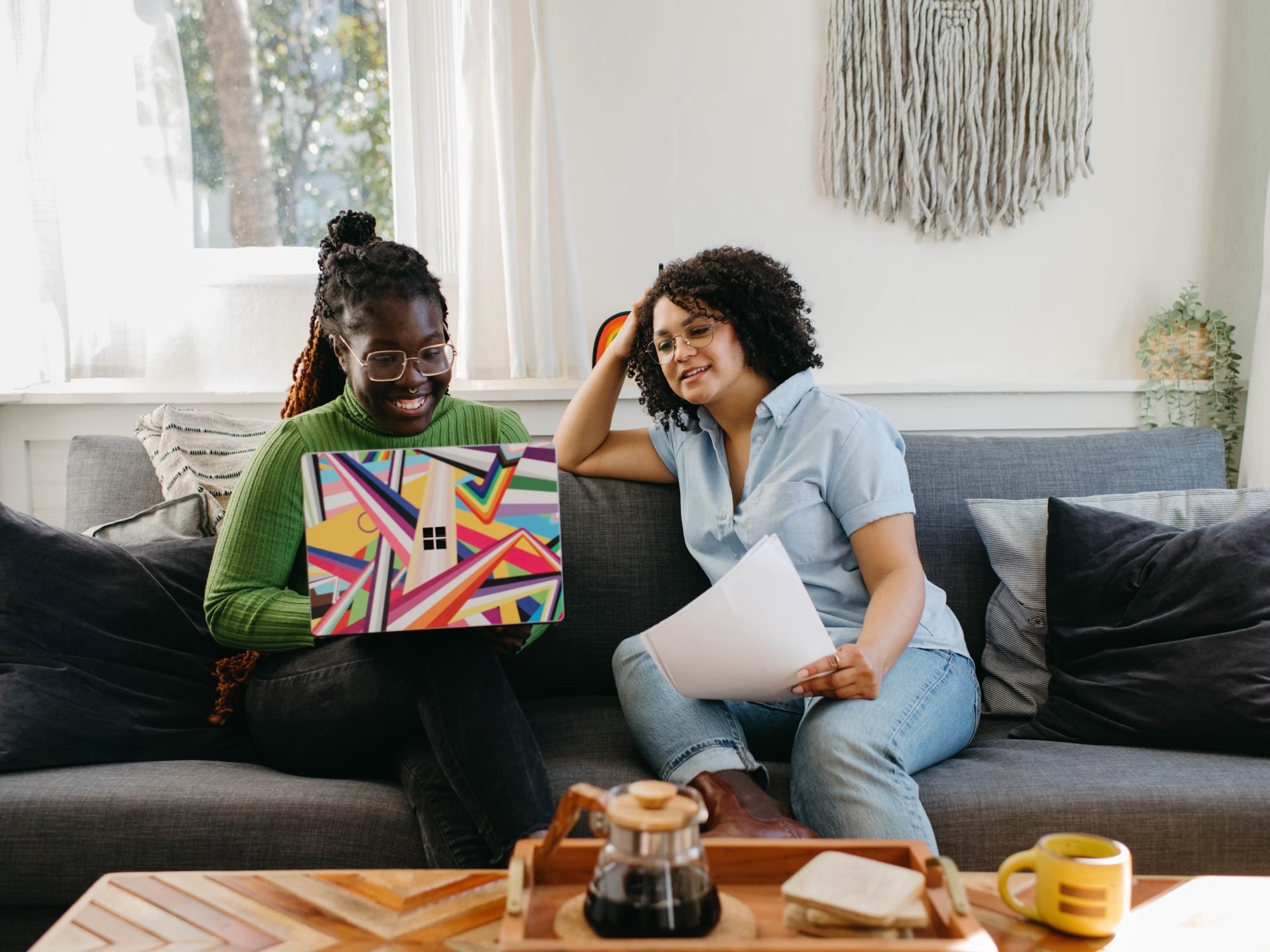 A carer and client reading paperwork together on a sofa at home